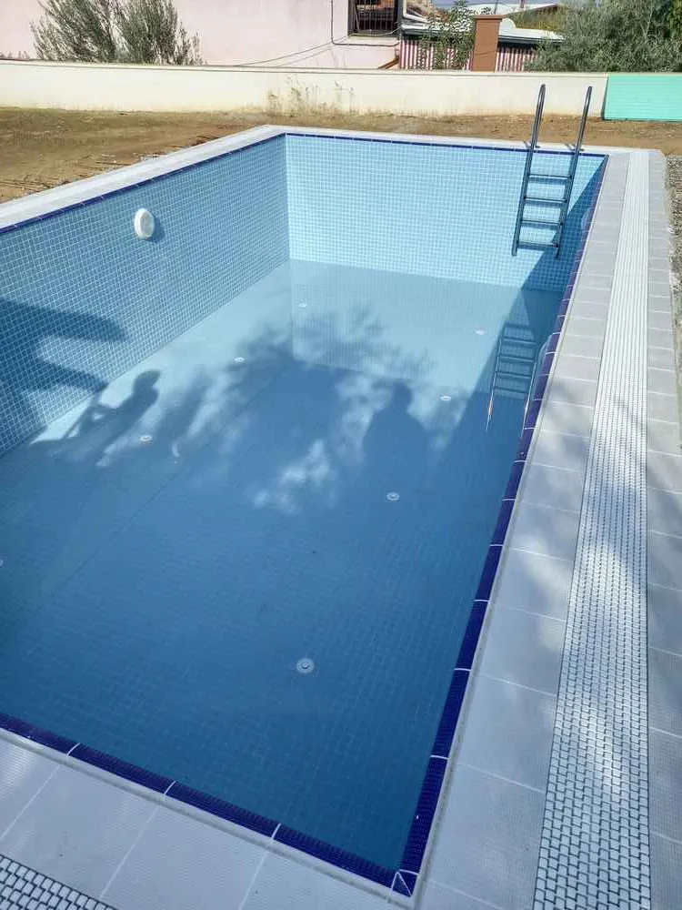 Mavi gökyüzü ve berrak suyuyla baş başa bir yüzme havuzu.